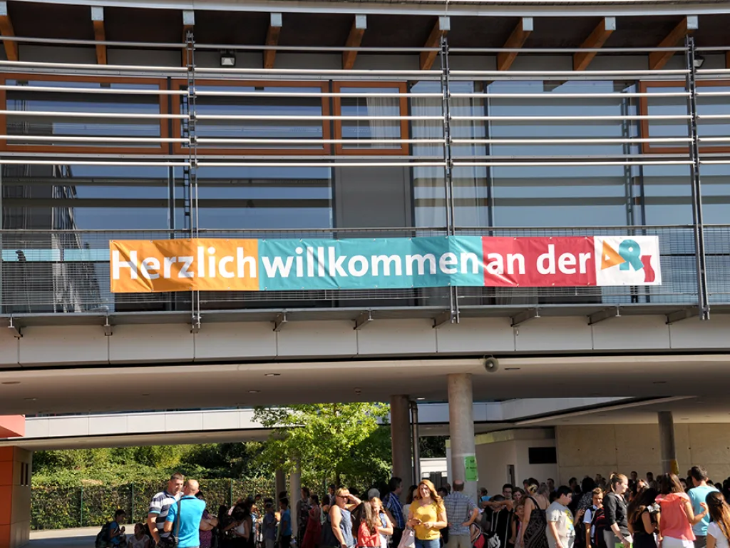 Über dem Schulhof hängt ein Banner mit der Aufschrift „Herzlich willkommen an der ARS“.
